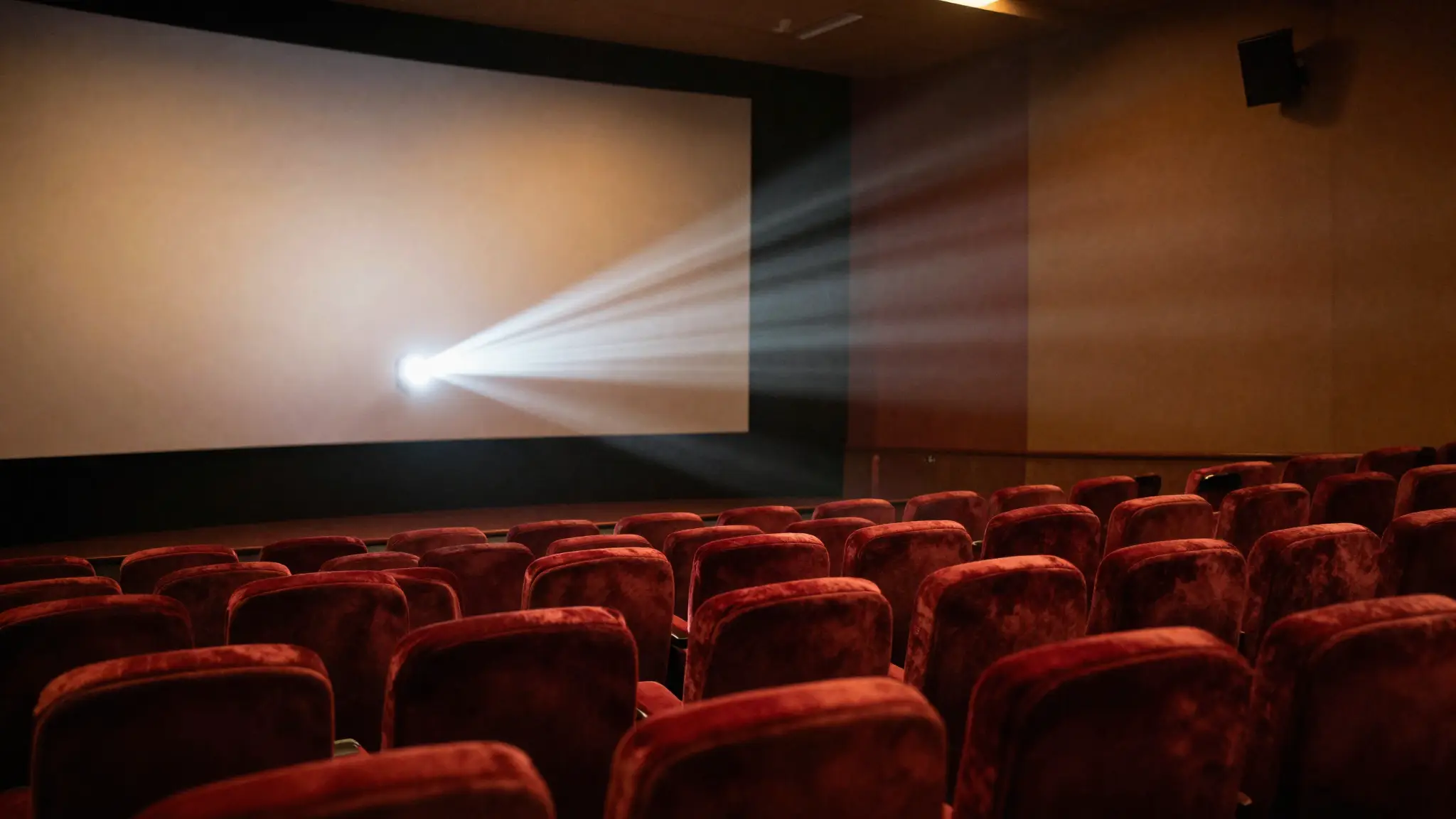 قاعة سينما فخمة بمقاعد حمراء وشاشة عرض مضيئة ترمز إلى عالم الأفلام